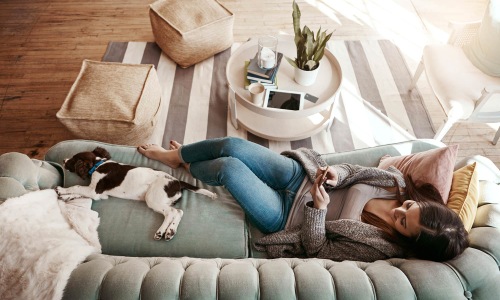 a woman laying on a couch beside her dog