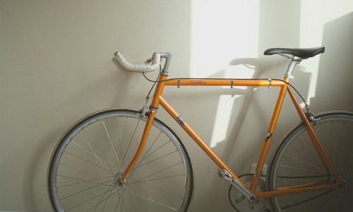 An orange bicycle sits against a wall in a room